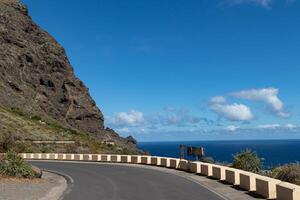 kurvig berg väg med hav se, klar blå himmel, och skyddsräcke i teneriffa. foto