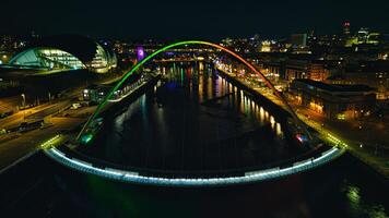 natt se av en stadsbild med upplyst välvd bro över en flod, reflekterande färgrik lampor på vatten i Newcastle på tyne foto