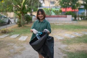 städa volontärer kvinna plockning löv och plast flaskor in i skräp sopor väskor, den begrepp av en rena naturlig miljö foto