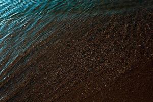 havsstrand av sand och snäckor täckt med saltvatten. foto