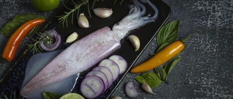 rå bläckfisk med grönsaker på en svart tallrik foto