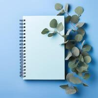 ai genererad elegant designad blå papper anteckningsbok Utsmyckad med eukalyptus löv på en lugn blå bakgrund. ai genererad foto