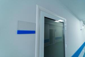 vit namnskylten nära de dörr. nödsituation dörr i vit korridor av sjukhus. foto