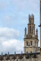 gotik torn stigande mot en molnig himmel, med invecklad arkitektonisk detaljer och sten balustrad i oxford, england. foto