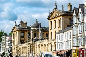 historisk europeisk stad gata med klassisk arkitektur och livliga fotgängare under en blå himmel med moln i oxford, england. foto