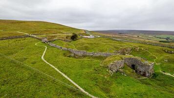 rullande grön kullar med en sten vägg och en ruin, under en molnig himmel, skildrar lantlig landskap. foto