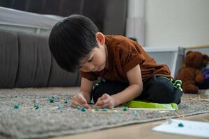 asiatisk pojke spelar med plastin i de rum foto
