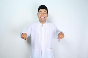 leende muslim asiatisk man ser på kamera med pekande ner Nedan isolerat på vit bakgrund foto