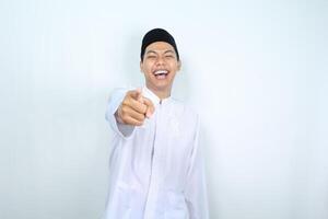 skrattande asiatisk muslim man pekande på kamera isolerat på vit bakgrund foto