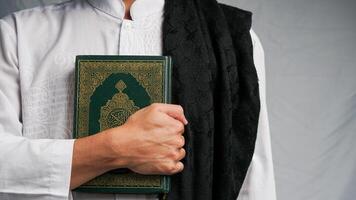 en man är fattande de koranen med en bön matta i hans hand foto