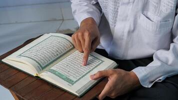 stänga upp Foto av en muslim man läsning de quran på en bön matta under de helig månad av ramadan.