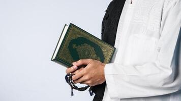 en muslim man bärande de quran med bön pärlor i hans händer. begrepp av de månad av ramadan foto