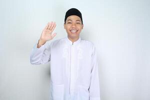 attraktiv muslim asiatisk man vinka hand sy Hej gest med leende isolerat på vit bakgrund, ser på kamera foto