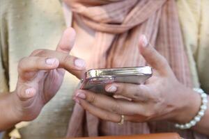 stänga upp av ung kvinnor hand använder sig av smart telefon. foto