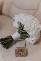 bröllop bukett. vit skära rosor, grön utsäde huvuden och löv. grön stjälkar och vit band och guld bröllop ringar. foto