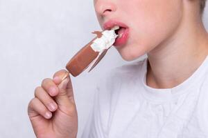en pojke vars ansikte är oigenkännlig äter is grädde täckt i choklad. foto