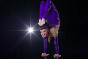 cirkus skådespelerska utför de siffra i en skön rök. manuell jämvikt på käppar. flexibel flicka kroppsprestanda av ett luft gymnast i en cirkus foto