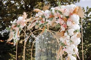 gyllene båge dekorerad med blommor på de bakgrund av träd. förberedelse för de bröllop ceremoni. allt är redo för de firande. foto