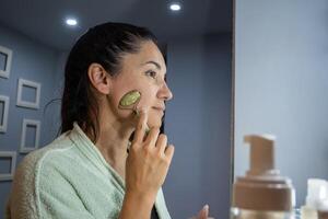 latin kvinna använder sig av jade ansiktsbehandling massageapparat. foto
