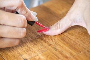 kvinna målning henne stor finger med en semipermanent nagel putsa. foto
