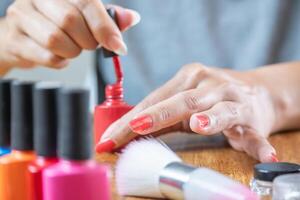 röd semipermanent nagel måla. de latin kvinna gäller den till henne naglar mycket försiktigt. foto