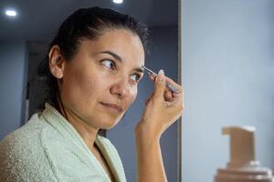 latin kvinna använder sig av ett ögonbryn pincett foto
