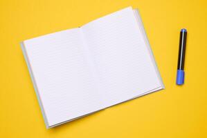 öppen anteckningsbok med tom vit ark på en gul bakgrund foto