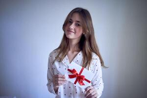 gåva certifikat i de händer av en Tonårs flicka bär vit pyjamas med röd hjärtan foto