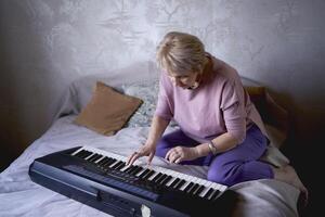 en 60-åring mor och en 40-åring dotter spela de tangentbord tillsammans på de säng på Hem foto