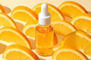naturlig vitamin c serum, hudvård, grundläggande olja Produkter. flaska av vitamin c serum med färsk saftig orange frukt. skönhet produkt branding mock-up foto