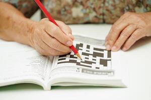 äldre kvinna spelar sudoku pussel spel för behandling demens förebyggande och alzheimers sjukdom. foto