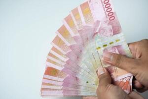 manlig hand innehav en massa av indonesiska pengar rupiah på en isolerat vit bakgrund. företag begrepp ,finansiell begrepp foto
