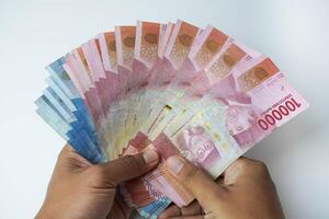 manlig hand innehav en massa av indonesiska pengar rupiah på en isolerat vit bakgrund. företag begrepp ,finansiell begrepp foto