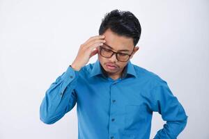 ung asiatisk man i bär blå skjorta innehav huvud lidande från huvudvärk eftersom migrän och yr isolerat på vit bakgrund foto