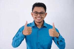 upphetsad glad asiatisk affärsman med glasögon bär blå skjorta isolerat över vit bakgrund, som visar tummen upp foto