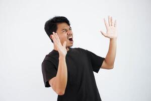 skrek eller chockade ung asiatisk man öppen hand med öppen mun bär svart t skjorta isolerat på vit bakgrund foto