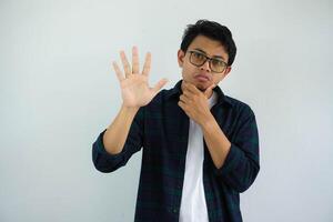 ung asiatisk man som visar nyfiken ansikte uttryck medan ger fem fingrar tecken isolerat på vit bakgrund foto