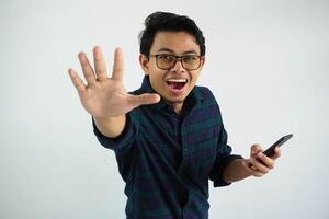ung asiatisk man som visar upphetsad uttryck innehav mobil telefon när påfrestande till hugg något den där falla från ovan isolerat på vit bakgrund foto