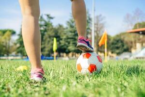 ung kvinna fotboll spelare Traning med boll i de stadion - sportig kvinna framställning övningar på de tåg fält - begrepp av sportigt människor livsstil foto