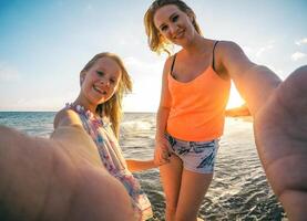 Lycklig kärleksfull familj mor och dotter tar en selfie på de strand på solnedgång - mamma med henne unge utgifterna tid på Semester - förälder, semester, familj livsstil begrepp foto
