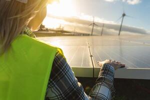 ung kvinna ingenjör arbetssätt för alternativ energi med vind turbin och solceller sol- panel - innovation och grön kraft begrepp foto