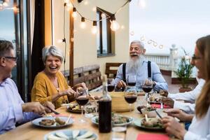 Lycklig senior vänner har roligt dining tillsammans på hus uteplats - äldre livsstil människor och mat begrepp foto