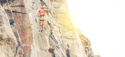 atletisk man klämning en sten vägg på solnedgång - klättrare utför på en kanjon berg framställning ett akrobatisk hoppa - begrepp av sport, extrem, resa livsstil foto