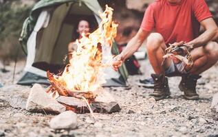 Lycklig par framställning brand medan camping i vild skog - ung människor har roligt reser och camping Nästa bål - resa semester livsstil begrepp foto