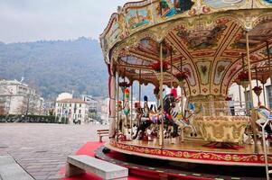 en glad gå runda, victorian karusell på jul fairground i como, mot italiensk alps bakgrund på molnig vinter- dag foto