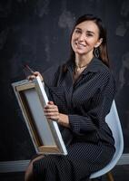 en ung brunett kvinna konstnär står Bakom ett staffli. foto