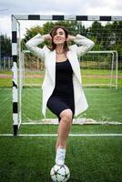 porträtt av en skön kvinna fotboll spelare i en sträng kontor kostym. foto