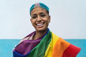 ung aktivist kvinna leende och innehav regnbåge flagga symbol av lgbtq social rörelse foto