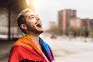 Lycklig Gay man har roligt innehav regnbåge flagga symbol av lgbtq gemenskap foto