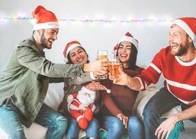 grupp av Lycklig vänner glädjande med öl på jul fest - ung människor har roligt dricka och njuter tillsammans xmas högtider - vänskap, drycker och ungdom fira livsstil begrepp foto